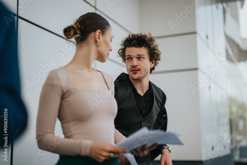 Two business professionals are seen discussing documents outside an office building. They appear to be engaged in a serious conversation.