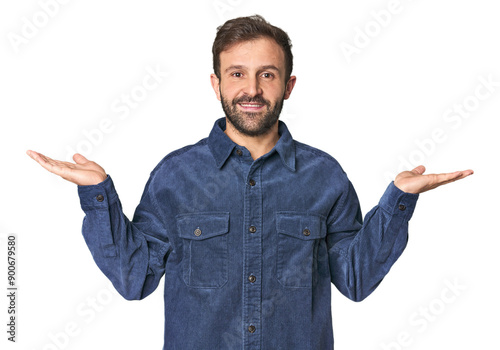 Studio portrait of young Hispanic male makes scale with arms, feels happy and confident.