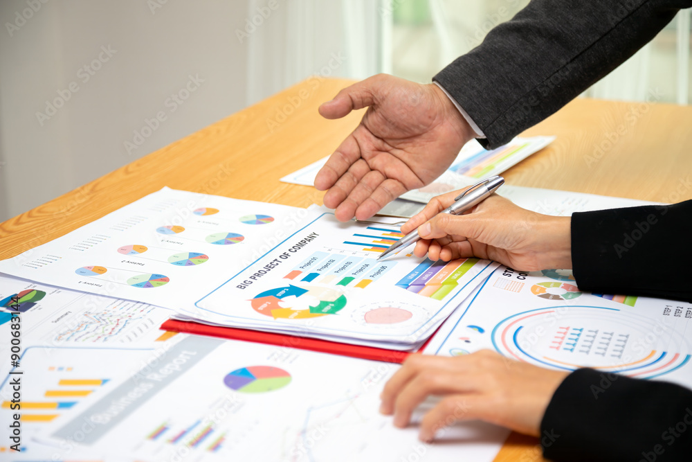 Two Business professionals discussing and reviewing project performance charts and graphs, focusing on strategic planning and company analysis during meeting Two Business professionals discussing and reviewing project performance charts and graphs, focusing on strategic planning and company analysis during meeting