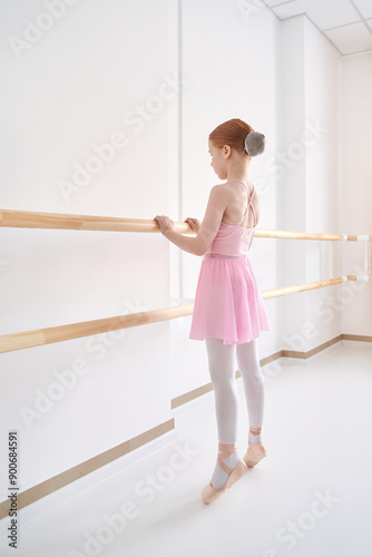 Young ballet girl at studio lesson. Training performance. Stretching exercise pose. Ballerina practice balance technique. Classical elegance fitness. Dancing costume. Pink dress, skirt