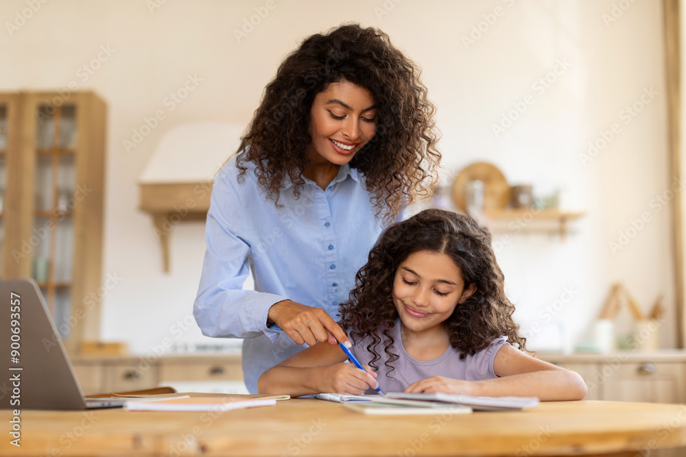 Mom helping schoolgirl daughter with homework or school project, preparing for test exam together, sitting at kitchen table at home Mom helping schoolgirl daughter with homework or school project, preparing for test exam together, sitting at kitchen table at home