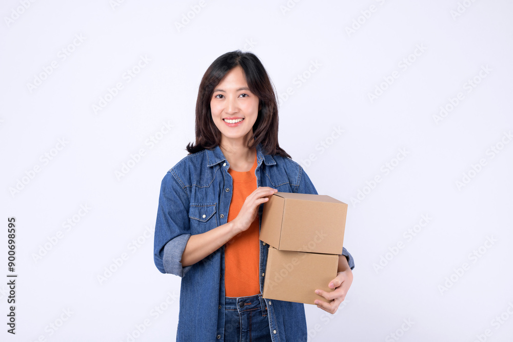 Portrait young asian woman wearing orange t-shirt and denim shirt holding parcel box isolated on white studio background, Delivery courier and shipping service concept. Portrait young asian woman wearing orange t-shirt and denim shirt holding parcel box isolated on white studio background, Delivery courier and shipping service concept.