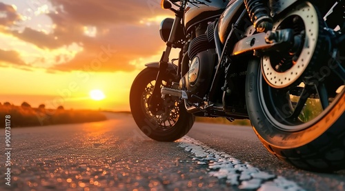  Close up of the front wheel and motorcycle on an empty road with a beautiful sunset in the background. 