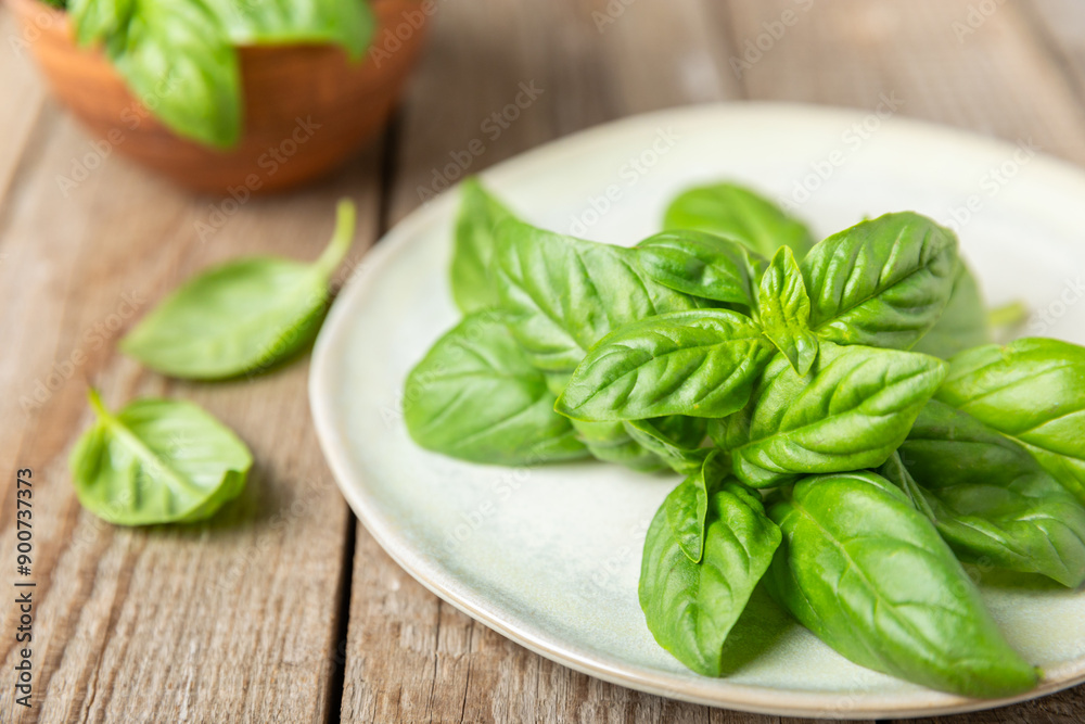 Green basil leaves on a textured wooden background. Kitchen herbs, spices. Fresh green organic basil. Vegan. Greens for salad. Place for text. Copy space. Green basil leaves on a textured wooden background. Kitchen herbs, spices. Fresh green organic basil. Vegan. Greens for salad. Place for text. Copy space.