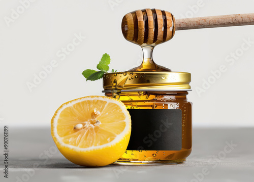 A jar of honey with a wooden ladle, a sprig of mint and a lemon cut in half on a clean white background photo