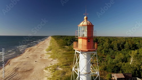 A bright red lighthouse on a background of blue sky and sea. Aerial photography