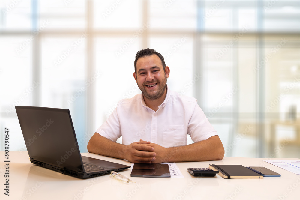A plaza employee smiles for the camera in front of a tablet and laptop. Digitalization in business life. Reduced workload. A plaza employee smiles for the camera in front of a tablet and laptop. Digitalization in business life. Reduced workload.