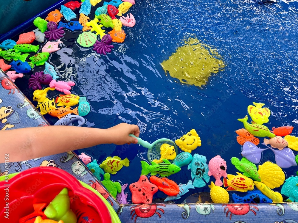Obraz premium Hand of the child playing in fishing game. Fish toys in a water