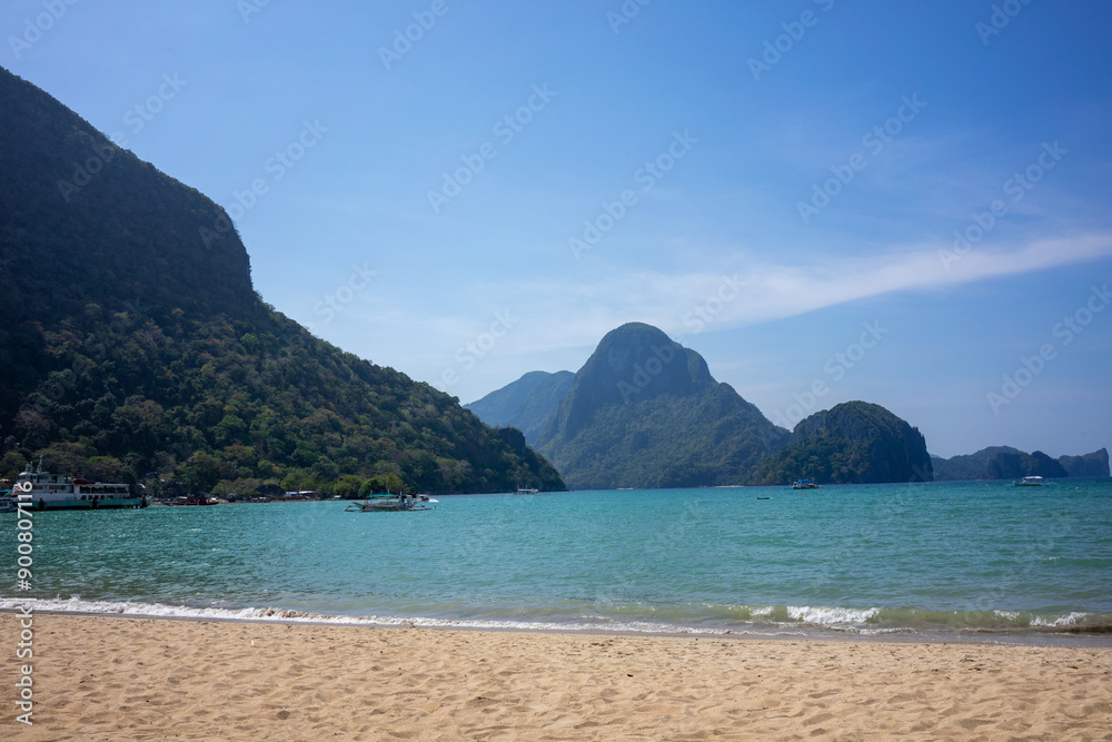 Expansive view of El Nido beach, Philippines, showcasing crystal clear waters and lush green hills under a vibrant blue sky Expansive view of El Nido beach, Philippines, showcasing crystal clear waters and lush green hills under a vibrant blue sky
