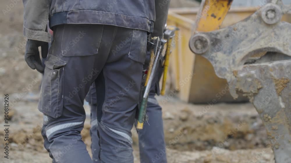 Ouvriers sur un chantier de construction avec leurs outils accrochés à la taille. Workers on a construction site with their tools hanging from their waists.