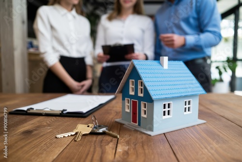 Creative mortgage concept with house, paperwork and keys on wooden office desktop. Businesspeople standing in the background.