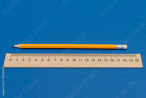 Pencil and wooden measuring ruler on blue background photo