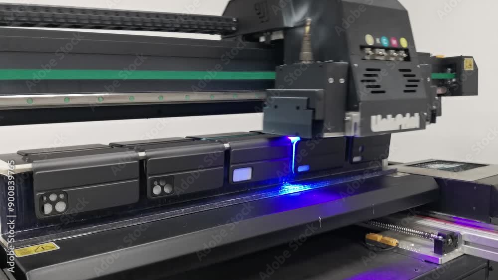A modern digital large-format UV printer prints images on smartphone cases. UV pinning is the process of applying a dose of low intensity ultraviolet light to a UV curable ink A modern digital large-format UV printer prints images on smartphone cases. UV pinning is the process of applying a dose of low intensity ultraviolet light to a UV curable ink