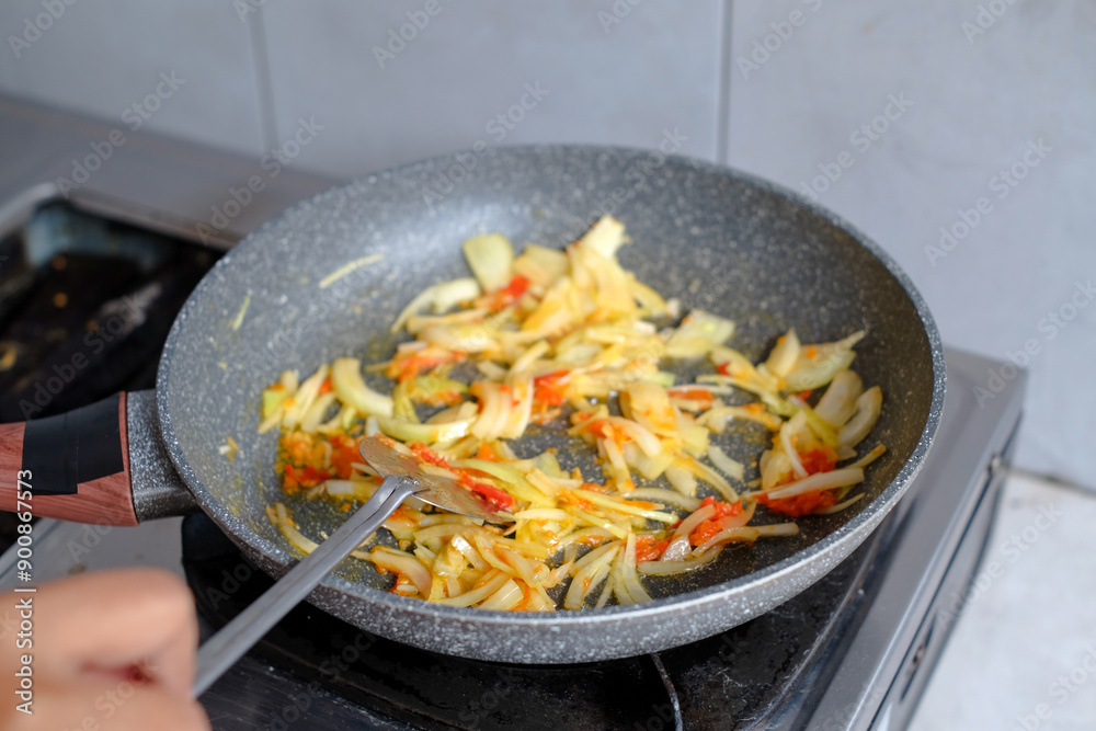 The cook stirs fried onions in a frying pan for spaghetti sauce, making spaghetti, culinary. Food background. The cook stirs fried onions in a frying pan for spaghetti sauce, making spaghetti, culinary. Food background.