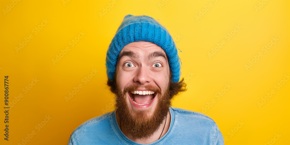 Excited young man with blue beanie is screaming of joy on yellow background Excited young man with blue beanie is screaming of joy on yellow background