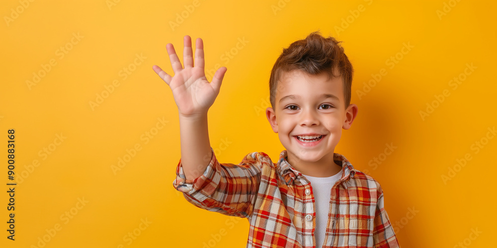 Cheerful boy waving hand and smiling on yellow background Cheerful boy waving hand and smiling on yellow background