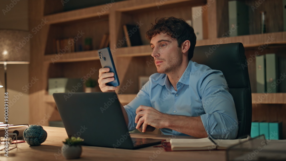 Freelancer looking cellphone drinking coffee at work desk late evening close up. Freelancer looking cellphone drinking coffee at work desk late evening close up.