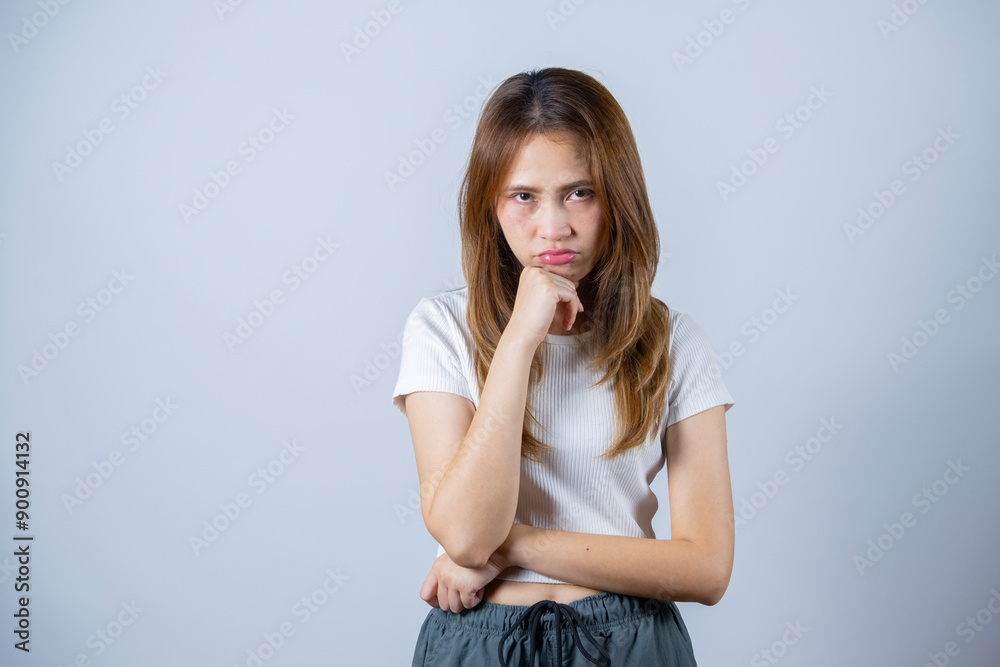 Young woman with long hair expressing contemplation and frustration with folded arms and hand on chin, white background. Young woman with long hair expressing contemplation and frustration with folded arms and hand on chin, white background.