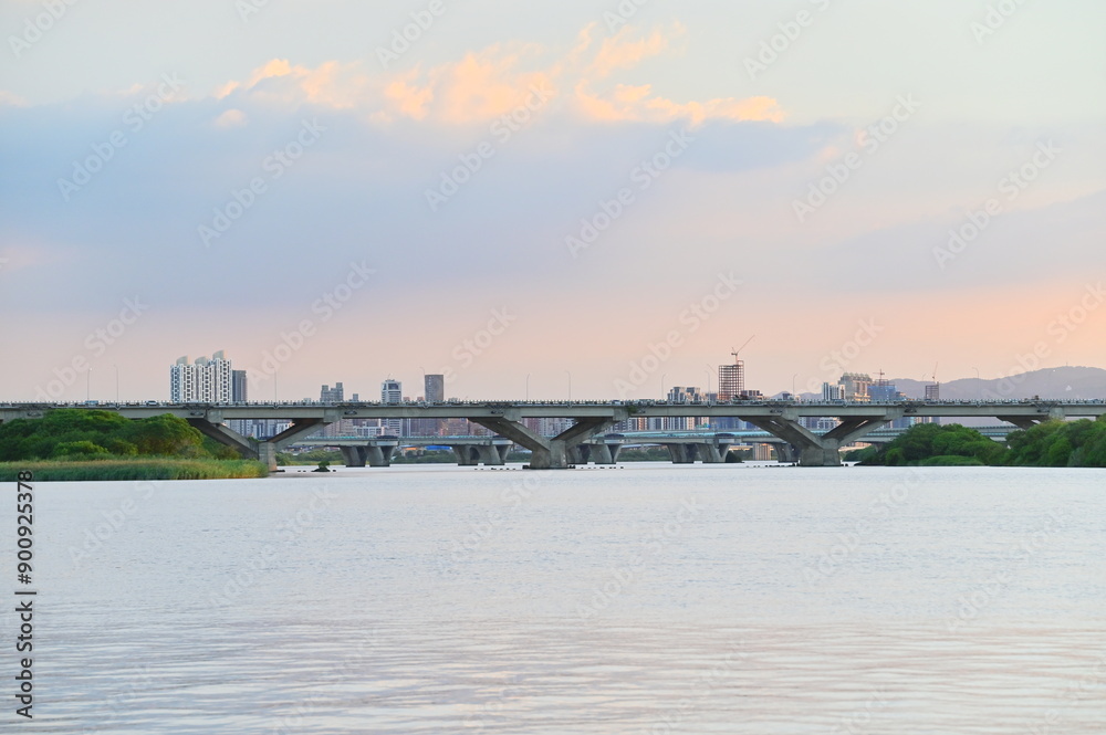 Fototapeta premium At twilight from Dadaocheng Pier, gaze across the Tamsui River to Banqiao in New Taipei City, where a mix of high-rise buildings and under-construction sites add dynamic color to the skyline.