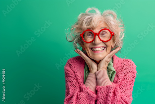 Happy smiling senior woman wearing sunglasses, green solid colorful background, image with space for text / Femme âgée souriante et heureuse avec lunettes de soleil, fond vert, espace pour le texte