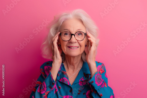 Happy smiling senior woman wearing sunglasses, pink solid colorful background, space for text / Femme âgée souriante et heureuse avec lunettes de soleil, fond rose, espace pour le texte