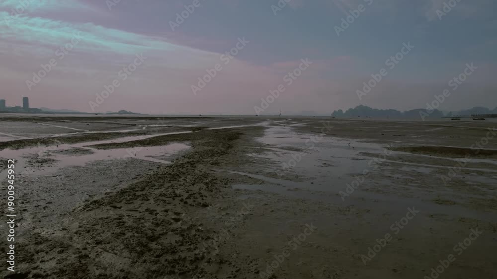Low drone shot flying over muddy, wet terrain during beautiful blue hour dusk sunset.