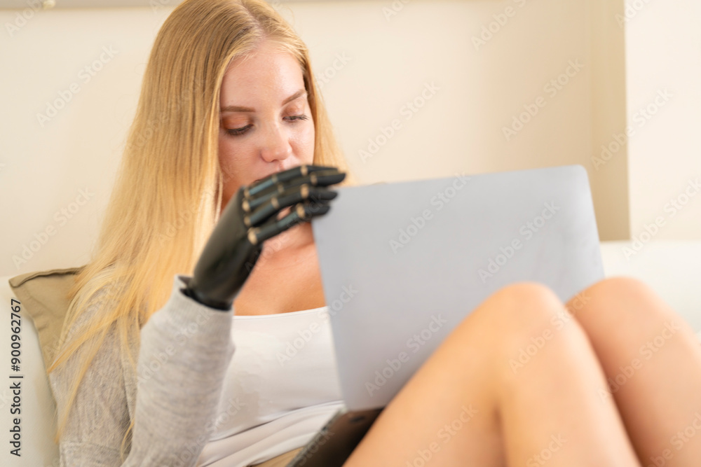 A young woman is using a robotic prosthetic arm hand attached to her body to work on a desk. she is doing computer document and communication work. woman tries to control the smart arm in her home. A young woman is using a robotic prosthetic arm hand attached to her body to work on a desk. she is doing computer document and communication work. woman tries to control the smart arm in her home.