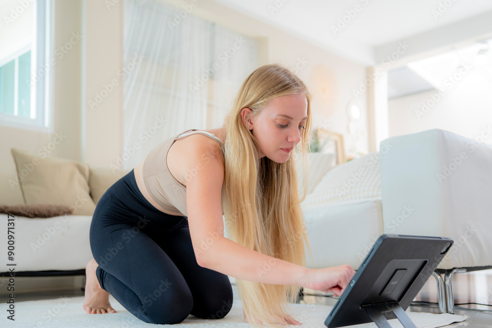 A young girl in tight workout clothes is practicing yoga poses by herself in her living room. She is doing basic warm up stretches. She is working her arms legs chest stomach hips and her whole body. A young girl in tight workout clothes is practicing yoga poses by herself in her living room. She is doing basic warm up stretches. She is working her arms legs chest stomach hips and her whole body.