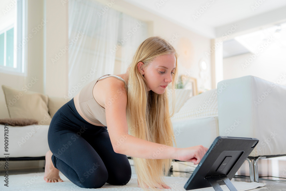 A young girl in tight workout clothes is practicing yoga poses by herself in her living room. She is doing basic warm up stretches. She is working her arms legs chest stomach hips and her whole body. A young girl in tight workout clothes is practicing yoga poses by herself in her living room. She is doing basic warm up stretches. She is working her arms legs chest stomach hips and her whole body.
