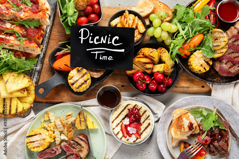 Table with grilled food. Pizza, corn, tomatoes, peppers, cooked meat. BBQ time Table with grilled food. Pizza, corn, tomatoes, peppers, cooked meat. BBQ time
