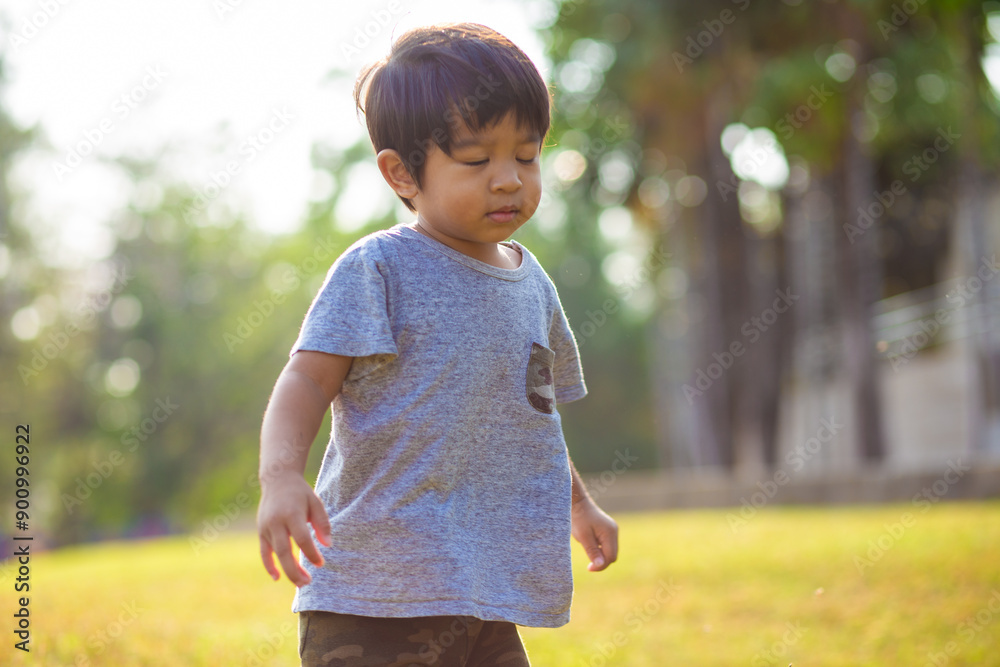 Adorable preschool little boy running on green grass city public park morning sun light Adorable preschool little boy running on green grass city public park morning sun light