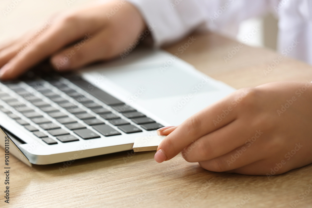 Woman with modern laptop and USB flash drive at wooden table, closeup
