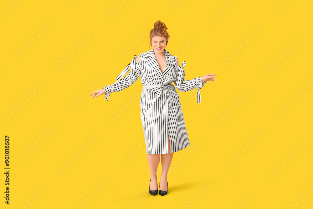 Beautiful young woman in stylish striped dress on yellow background Beautiful young woman in stylish striped dress on yellow background