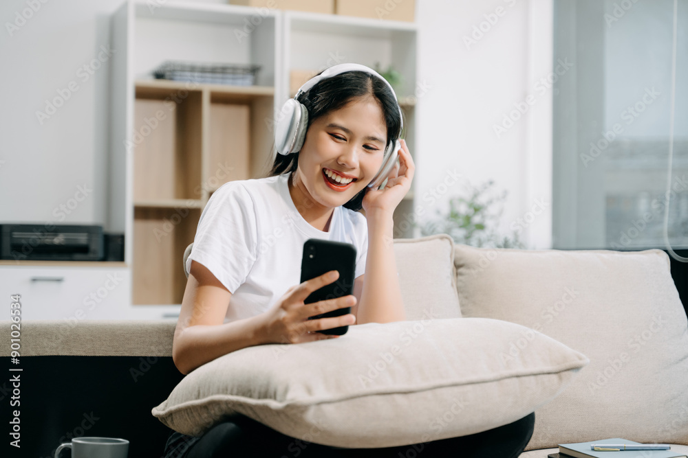 Young asian woman using smartphone and tablet while seated on couch Young asian woman using smartphone and tablet while seated on couch