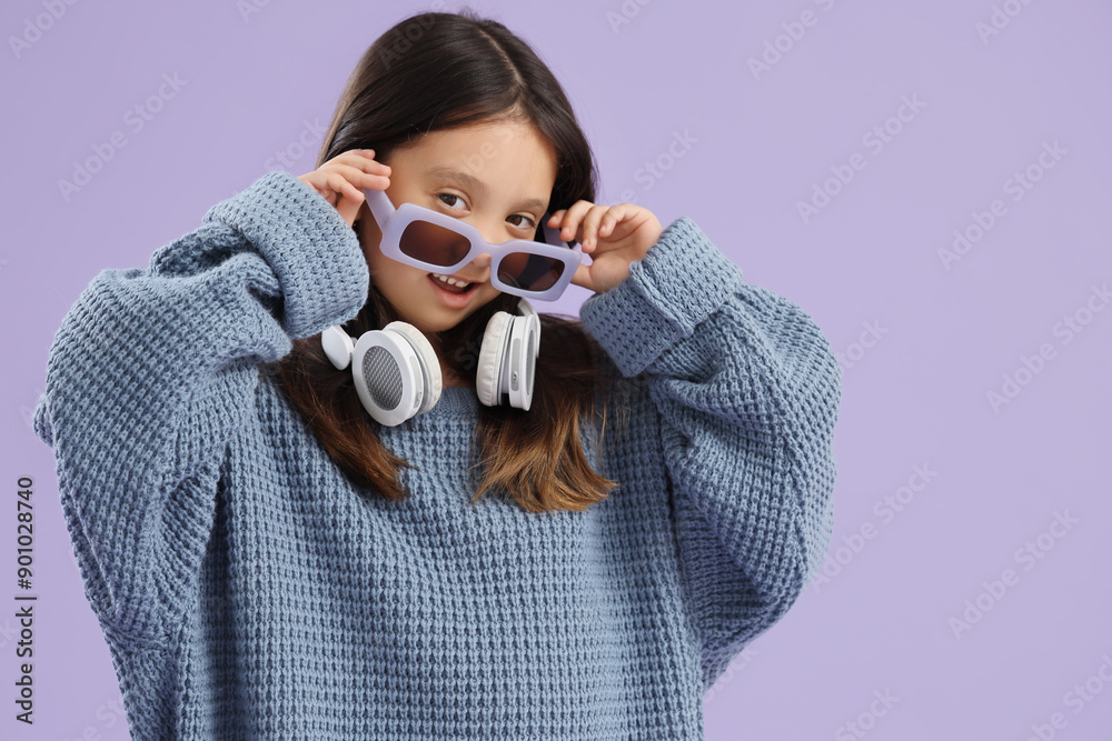 Cute little Asian girl in oversized sweater on lilac background Cute little Asian girl in oversized sweater on lilac background