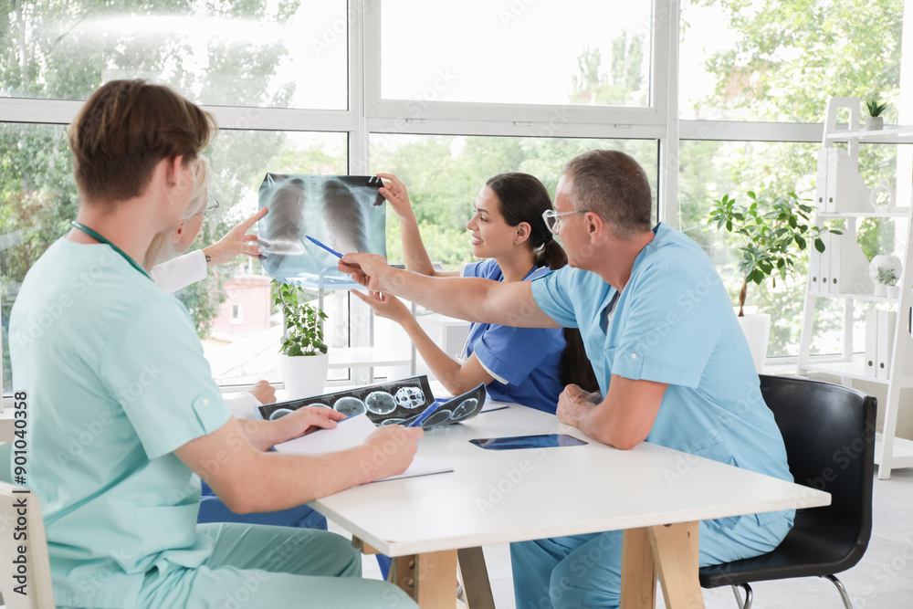 Obraz premium Group of doctors studying x-ray image of lungs at table in clinic