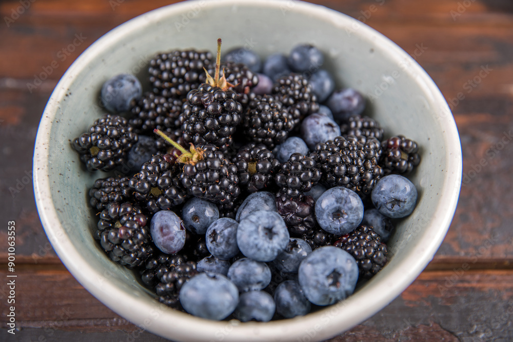 Ripe black blackberries and blue blueberries on a wooden table Ripe black blackberries and blue blueberries on a wooden table