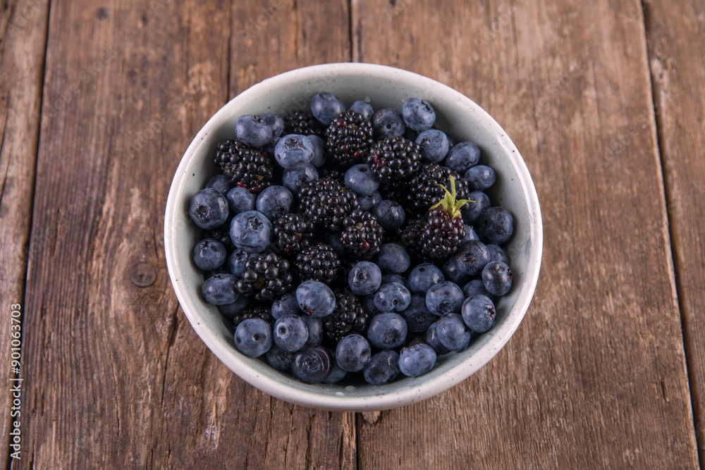 Ripe black blackberries and blue blueberries on a wooden table Ripe black blackberries and blue blueberries on a wooden table