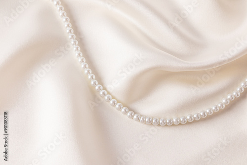 Chic wedding background beige, cream satin with soft waves of fabric and string of pearl beads. A copy of the space. cover, postcard, album.