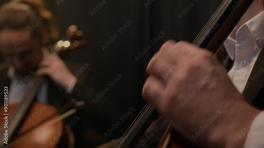 Tilt shot of professional string quartet in elegant black outfits performing music on dark background Tilt shot of professional string quartet in elegant black outfits performing music on dark background