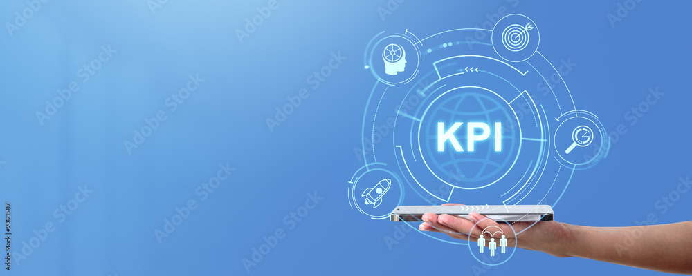 Hand holding tablet with KPI hologram on blue background.