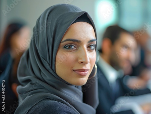 A woman wearing a headscarf stands among a crowd or group, possibly in a public place photo