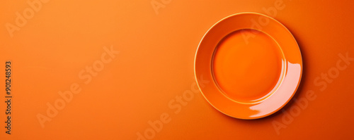 Festive design with a blank orange plate on an orange table, viewed from above. The warm orange theme adds energy to the celebration. Ample space for text. photo