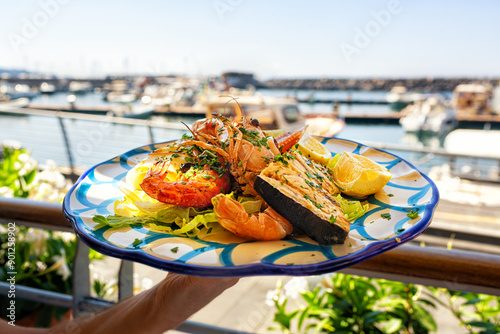 Fototapeta Naklejka Na Ścianę i Meble -  Serving Seafood and fish lunch in sea coast restaurant, Sicily, Italy. Italian food. Outdoor. Port with yacht on background.