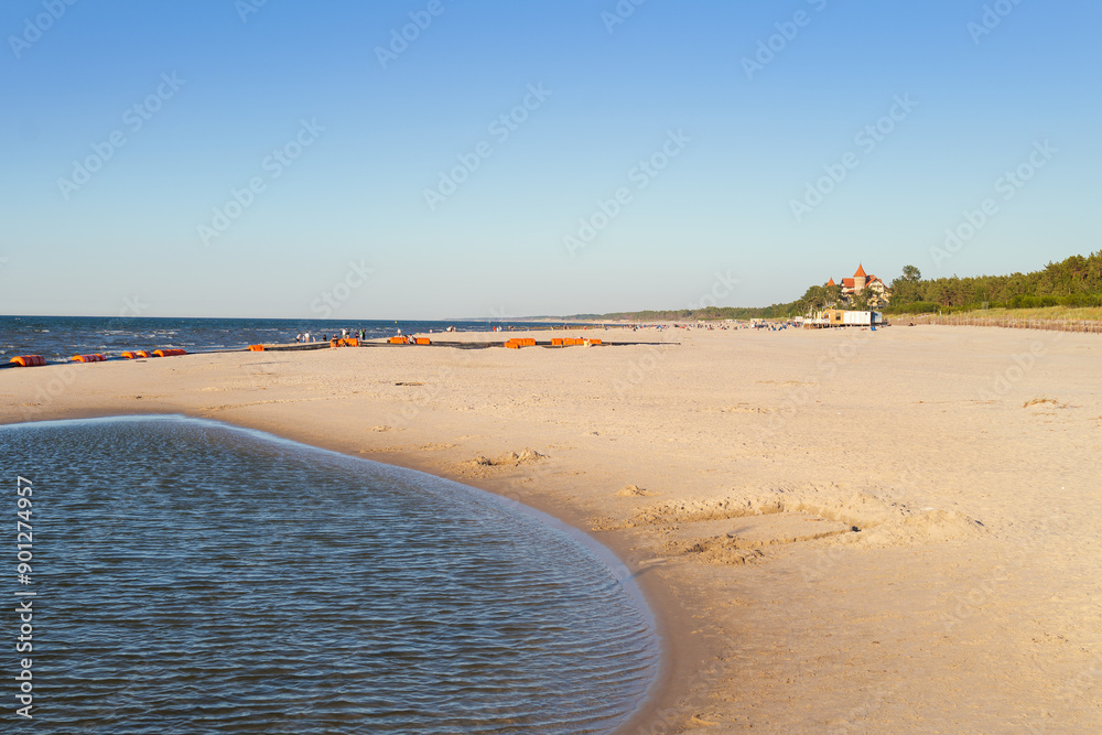 View of the beach in Leba. Beautiful wide beach on a sunny day. Castle and people in the distance. Leba, Poland