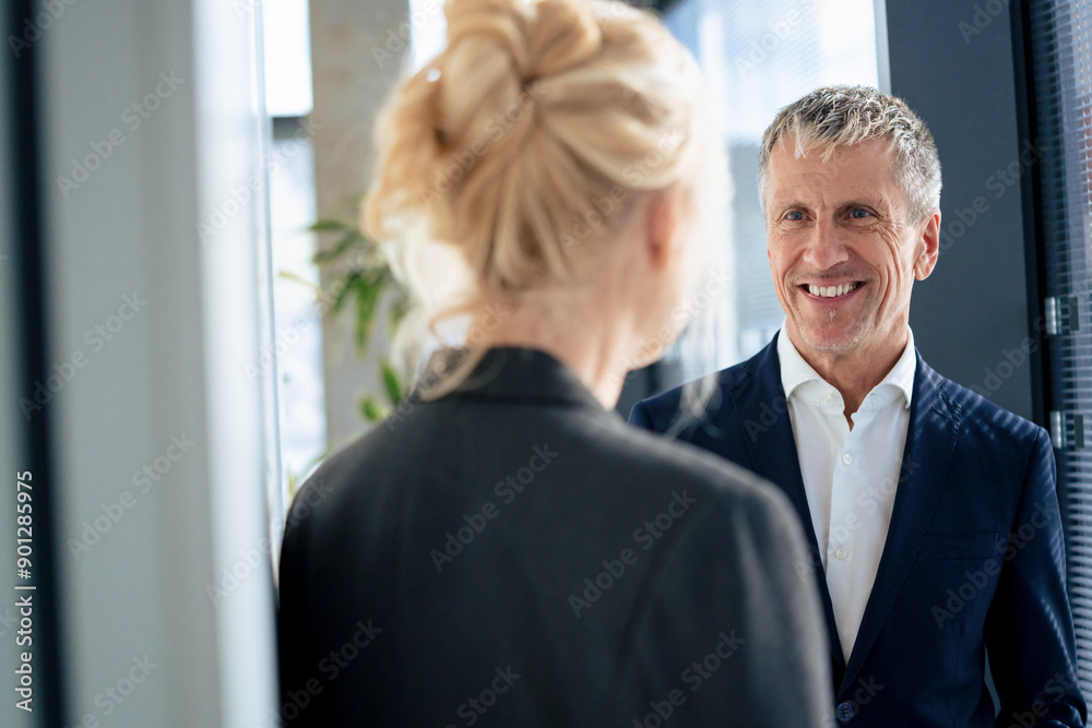 Smiling senior businessman looking at colleague Smiling senior businessman looking at colleague
