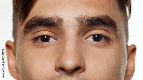 Close-up photo of male eyes, thick eyebrows against white studio background. Preorbital zone with well-kept skin. Concept of beauty, facial care, cosmetology procedures, wellness, masculinity. Ad photo