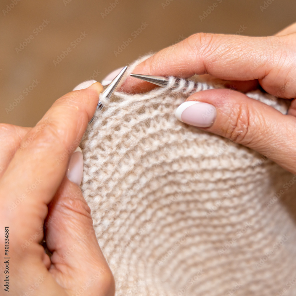 Obraz premium Close up of hands of unrecognizable woman knitting handmade clothes with spokes using wool yarn. Concept of leisure activity.Knitting from yarn on coarse spokes.