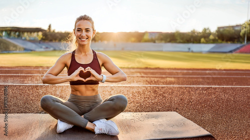 An athlete making a heart shape with her hands at a running track