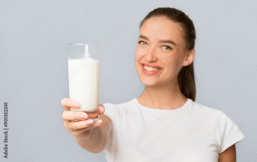 Dairy Products Benefits. Girl Offering Glass Of Milk To Camera Standing Over White Studio Background. Isolated, Shallow Depth Dairy Products Benefits. Girl Offering Glass Of Milk To Camera Standing Over White Studio Background. Isolated, Shallow Depth
